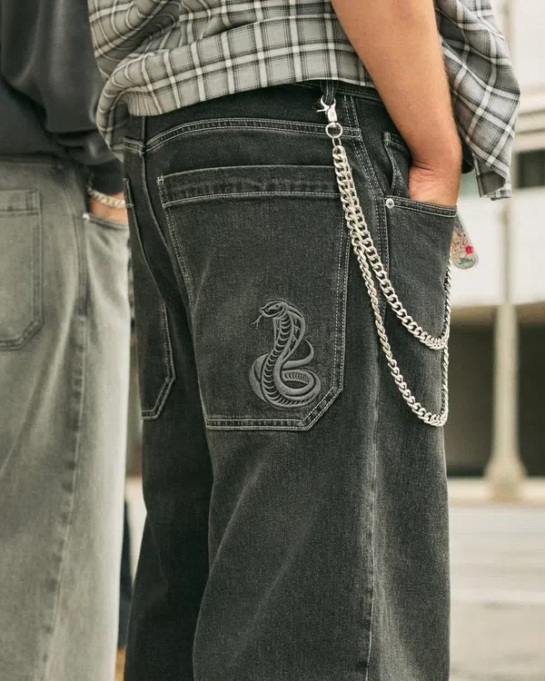 Gewaschene schwarze Baggy-Jeans mit Schlangenstickerei Gewaschene schwarze Baggy-Jeans mit Schlangenstickerei
